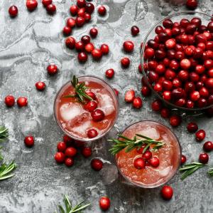 Whole cranberries in a bowl and placed within a drink in a glass.