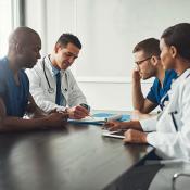 A meeting of 4 medical professional around a table.