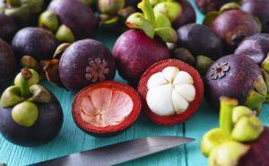A picture of Mangosteen as whole fruit and cut open.