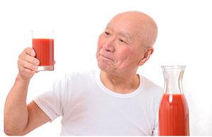 Image of a man holding up a glass of tomato juice.