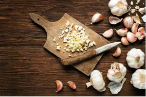 Whole garlic, garlic cloves, and chopped garlic displayed on a table.