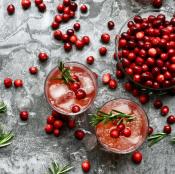 Whole cranberries in a bowl and placed within a drink in a glass.